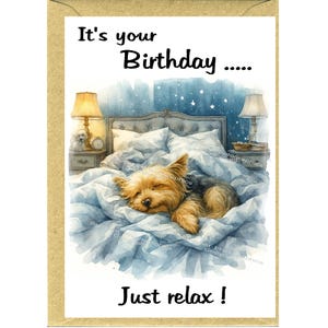 May include: A birthday card with a watercolour illustration of a Yorkshire Terrier dog asleep in a bed. The bed has blue bedding. The card's text reads "It's your Birthday..... Just relax!" on a white background.