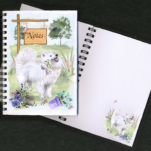 Puede incluir: Un perro blanco y esponjoso con una mariposa rosa en la portada de un cuaderno de espiral. El cuaderno tiene un cartel que dice "Notas" colgado de él. El perro está rodeado de flores y plantas.