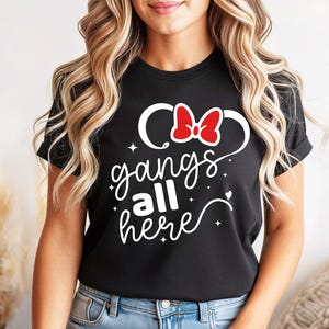 K&ouml;nnte beinhalten: Schwarzes T-Shirt mit wei&szlig;-roter Schleife und dem Schriftzug "gangs all here" in Schreibschrift. Das T-Shirt hat einen Rundhalsausschnitt und wird getragen.