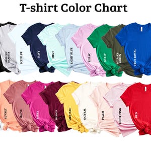 K&ouml;nnte beinhalten: Eine Farbkarte mit T-Shirts in verschiedenen Farben, darunter Schwarz, Wei&szlig;, Marineblau und Rot. Das Bild zeigt eine Vielzahl von T-Shirt-Farben mit Namen wie "Athletic Heather", "Ice Blue" und "True Royal". Der Text "T-shirt Color Chart" steht oben.
