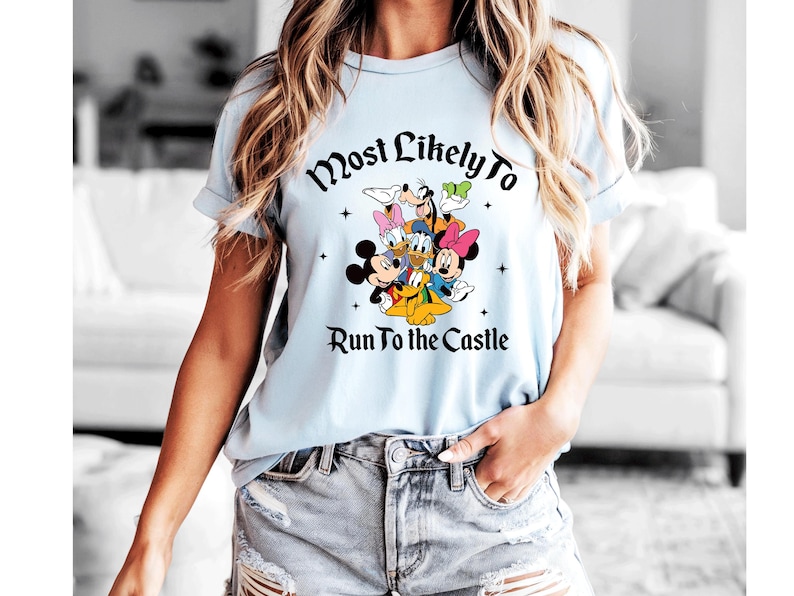 May include: Light blue t-shirt featuring a graphic of Disney characters including Mickey Mouse, Minnie Mouse, Donald Duck, Daisy Duck, Goofy, and Pluto. The text "Most Likely To Run to the Castle" is printed above the characters.