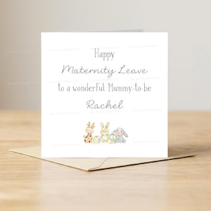 Può includere: Biglietto di auguri bianco con il testo "Happy Maternity Leave to a wonderful Mummy-to-be Rachel". Presenta illustrazioni di una giraffa, un coniglio e un elefante grigio. Il biglietto è su una busta marrone.