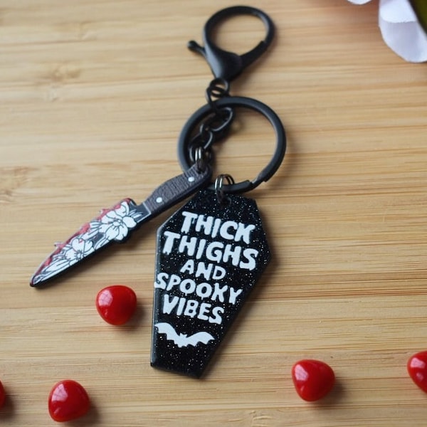 Thick Thighs & Spooky Vibes keychains, sparkly with gothic charm.
