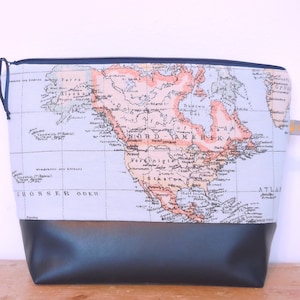 Könnte beinhalten: Eine rechteckige Reisetasche mit Weltkartenmuster auf der oberen Hälfte und einem schwarzen Boden. Die Karte zeigt Nordamerika in Orange-, Blau- und Weißtönen. Die Tasche hat einen marineblauen Reißverschluss und eine kleine Schlaufe.