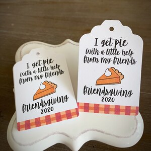 May include: Two white gift tags with a pie graphic and the text "I get pie with a little help from my friends" and "friendsgiving 2020". The tags have a red and orange plaid border.
