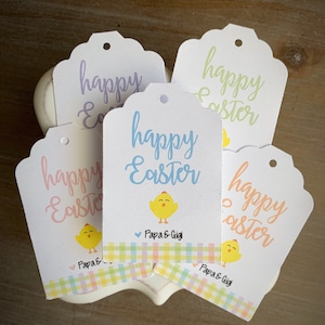 Puede incluir: Cinco etiquetas de regalo blancas con bordes festoneados y un agujero perforado en la parte superior. Cada etiqueta presenta una ilustraci&oacute;n de un pollito amarillo y el texto "happy Easter" en una fuente de letra cursiva colorida. Las etiquetas tienen un borde a cuadros en colores pastel y el texto "Papa & Gigi" en la parte inferior.