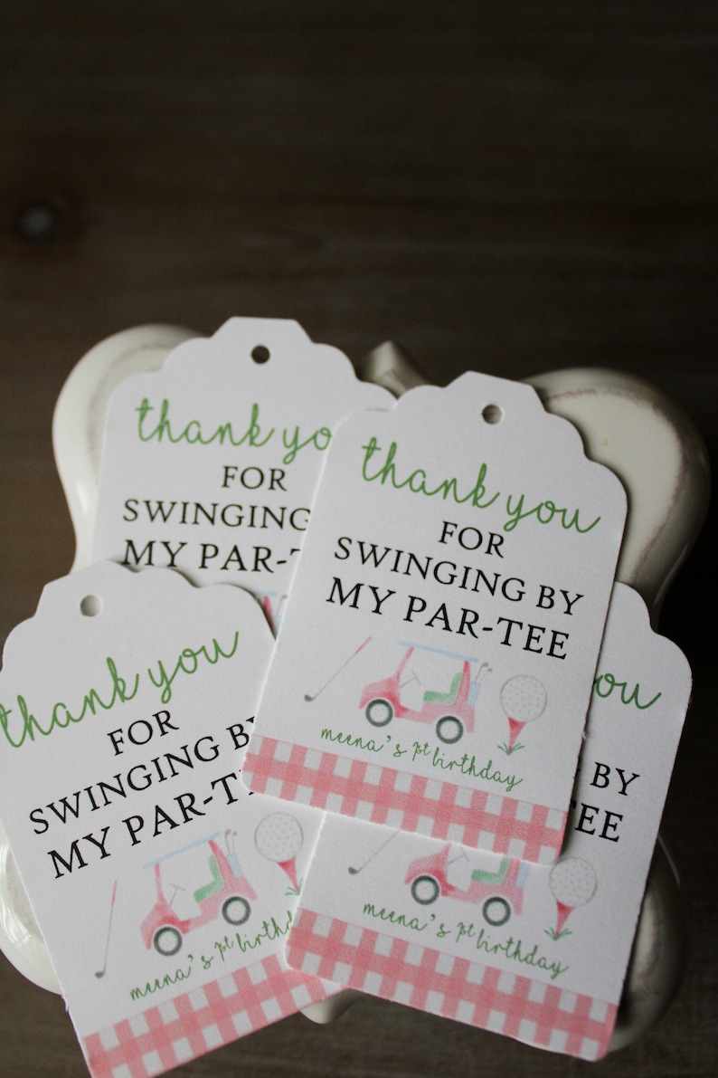 May include: Four white thank you tags with green and black text. The tags feature a golf cart and golf balls with a pink and white gingham pattern. The text on the tags reads "Thank you for swinging by my par-tee".