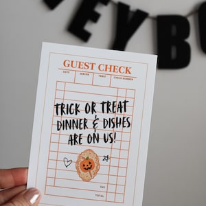 May include: A white rectangular guest check card with orange grid lines and text that reads GUEST CHECK, TRICK OR TREAT DINNER & DISHES ARE ON US!, DATE, SERVER, TABLE, CHECK NUMBER, TAX, and TOTAL. A small orange pumpkin illustration is included.