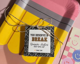 May include: A pencil-shaped paper plate with a square tag tied with twine. The tag reads "YOU DESERVE A BREAK Dinner + dishes are on us!" with a heart and "Love, Levi". Smiley face stickers are also visible.