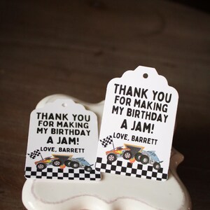 May include: Two white gift tags with a scalloped top edge, featuring the text "THANK YOU FOR MAKING MY BIRTHDAY A JAM! LOVE, BARRETT." Each tag has a race car graphic and a checkered flag border.