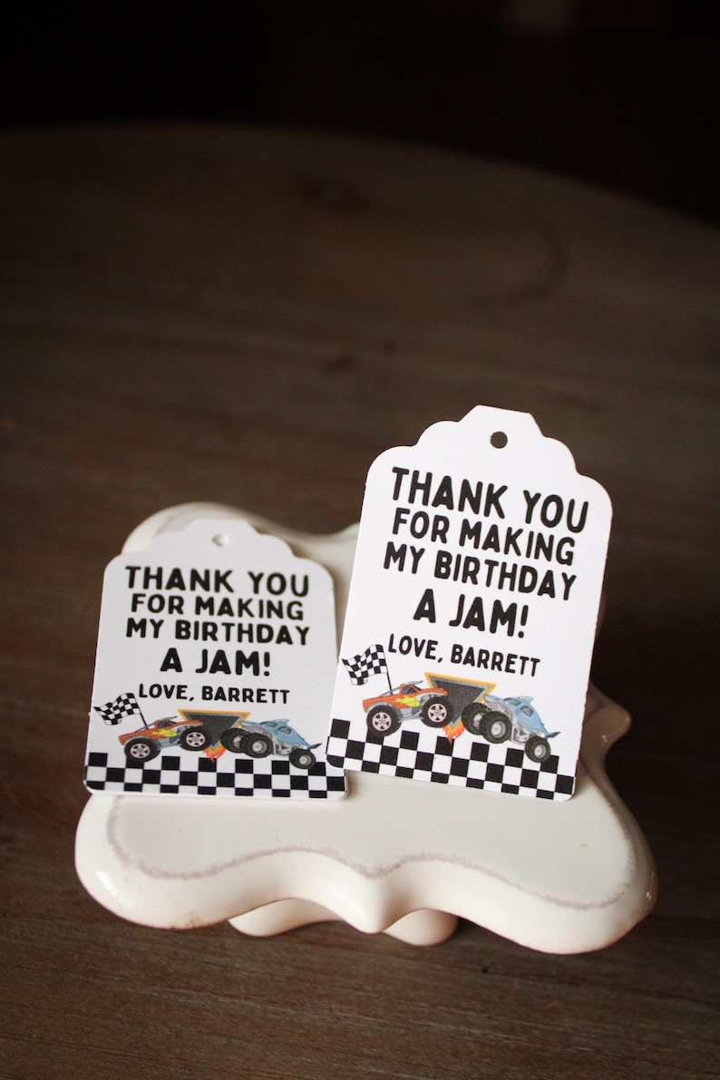 May include: Two white gift tags with a scalloped top edge, featuring the text "THANK YOU FOR MAKING MY BIRTHDAY A JAM! LOVE, BARRETT." Each tag has a race car graphic and a checkered flag border.