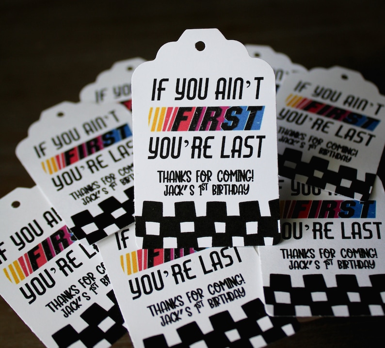 Puede incluir: Un conjunto de etiquetas de regalo blancas con patrones de cuadros en blanco y negro y el texto "If you ain't first you're last" en negro y rojo. Las etiquetas tambi&eacute;n incluyen el texto "Thanks for coming! Jack's 1st birthday".