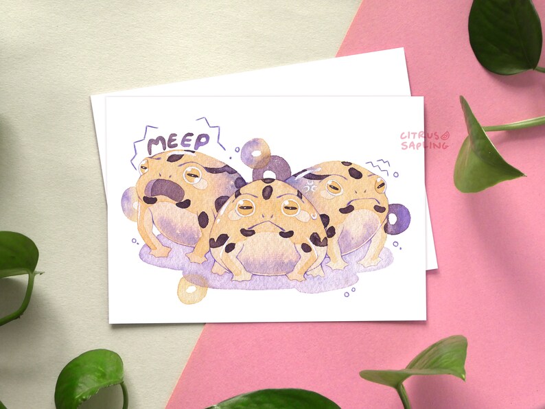 May include: A watercolor illustration of three cartoon frogs with black spots and yellow bellies. The frogs are on a purple background with white dots. The text "MEEP!" is above the frogs.