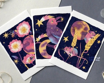 May include: Three watercolor illustrations on white cardstock. The first card features a pink flower with a bee, the second card features a purple bird with a yellow crescent moon, and the third card features two mice with a yellow crescent moon and wheat stalks.