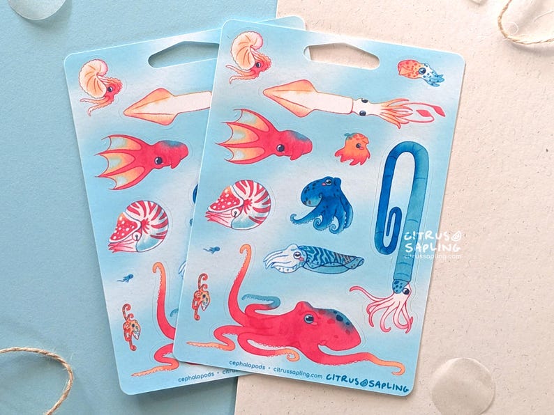 May include: Two sticker sheets featuring colorful illustrations of various cephalopods, including octopuses, squid, and nautilus shells. The stickers are on a light blue background with a small hole at the top. The text "CITRUS SAPLING" is visible on the right side.