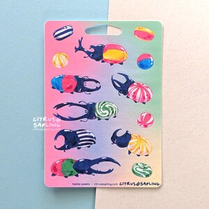 May include: A sticker sheet featuring colorful illustrations of beetles and candies. The beetles are depicted with various patterns and colors, such as red, yellow, blue, and green. The candies are round and striped. The text "beetle sweets" is visible.