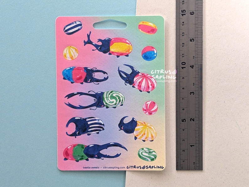 May include: A sticker sheet featuring colorful illustrations of beetles with candy-like designs. The beetles are in various colors, including blue, red, yellow, and green. The text "beetle sweets - citrussapling.com" is visible.