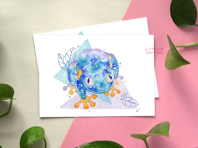 May include: A watercolor illustration of a blue and purple frog with orange feet and white spots. The frog is sitting on a purple and blue geometric background with leaves.