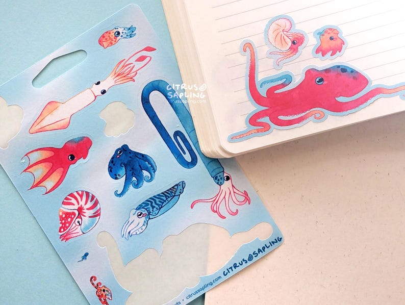 May include: A sheet of sea creature stickers and a notebook. The stickers feature colorful illustrations of an octopus, squid, nautilus, and other marine life. The notebook has a pink octopus sticker on the corner. The brand name "CITRUS@SAPLING" is visible.