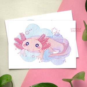 May include: A pink and blue watercolor illustration of an axolotl with large eyes, surrounded by clouds and flowers. The axolotl is swimming in a cloud-like shape. The illustration is signed "Citrus Sapling".