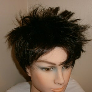 May include: A mannequin head with short, black, spiky hair. The mannequin has a neutral expression and is wearing a white shirt.