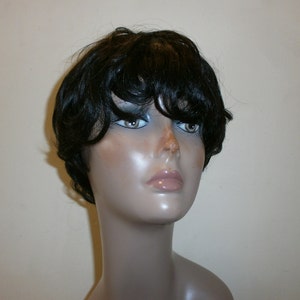 May include: A short black wig with a side parting and a layered, choppy style. The wig is styled with loose curls and has a natural-looking finish.