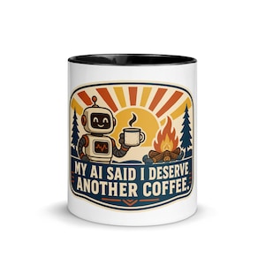 Puede incluir: Una taza de cerámica blanca con interior y borde negros, que presenta un gráfico de un robot sosteniendo una taza de café junto a una fogata. El diseño incluye un sol, pinos y el texto, MY AI SAID I DESERVE ANOTHER COFFEE.