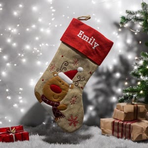 May include: A personalised Christmas stocking with a red felt cuff and a burlap body. The stocking features a brown reindeer with a red nose and a red Santa hat. The name "Emily" is embroidered in white on the cuff.