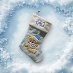 Può includere: Un calzino di Natale blu con un polsino bianco e un design a orsacchiotto. Il polsino è ricamato con "1° Natale di Adam".
