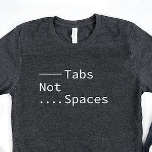 Puede incluir: Una camiseta gris oscuro con el texto "Tabs Not ... Spaces" impreso en blanco.