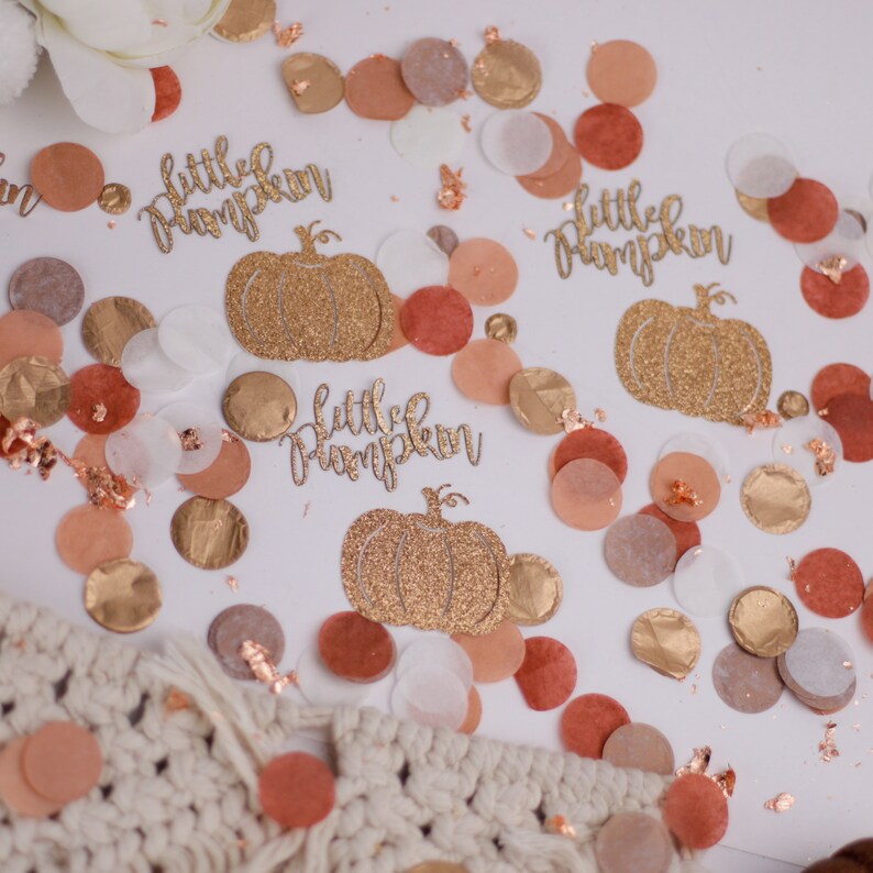May include: Gold glitter confetti with the text "little pumpkin" and a gold glitter pumpkin image. The confetti is on a white background with peach, brown, and gold confetti.