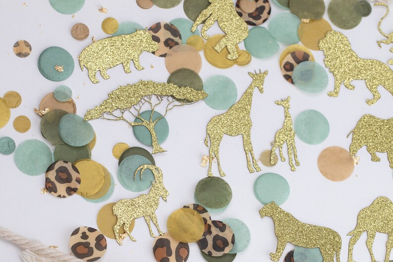 May include: Safari-themed confetti with gold glitter animal cutouts, including giraffes, lions, and elephants, scattered among green, brown, and leopard print circles. Gold leaf accents add a touch of sparkle to this decorative party supply.