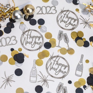 Peut inclure: Une composition festive du Nouvel An avec des confettis, des bouteilles et des verres de champagne. Des boules disco argentées et dorées et le chiffre 2023 sont dispersés parmi les confettis. Les mots "Happy New Year" sont dans un cercle.
