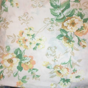 May include: A floral pattern featuring large, stylized flowers in shades of yellow, peach, and green against a cream background. The design includes detailed leaves and stems, creating a vintage aesthetic. This pattern is suitable for fabric or wallpaper.