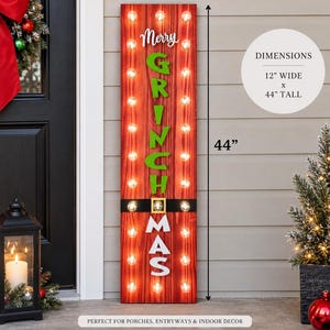 May include: A tall, rectangular red wooden sign with vertical wood grain, featuring the white and green text Merry GRINCH MAS. The sign includes a black belt graphic with a gold buckle and illuminated light bulbs. It measures 12 inches wide by 44 inches tall.