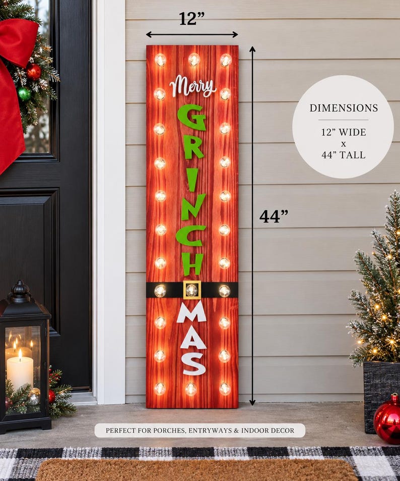 May include: A tall, rectangular red wooden sign with vertical wood grain, featuring the white and green text Merry GRINCH MAS. The sign includes a black belt graphic with a gold buckle and illuminated light bulbs. It measures 12 inches wide by 44 inches tall.
