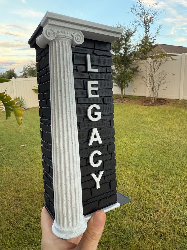 May include: A decorative pillar with the word "LEGACY" in white letters. The pillar has a black stone-like texture and a white column on the left side. The top and base are also white.