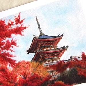 Puede incluir: Pintura a la acuarela de una pagoda japonesa con tejado rojo y azul, rodeada de vibrante follaje oto&ntilde;al rojo. La obra captura los detalles arquitect&oacute;nicos y la belleza estacional del paisaje.