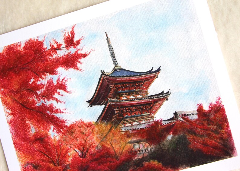 Puede incluir: Pintura a la acuarela de una pagoda japonesa con tejado rojo y azul, rodeada de vibrante follaje oto&ntilde;al rojo. La obra captura los detalles arquitect&oacute;nicos y la belleza estacional del paisaje.