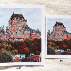 May include: Two art prints of a grand, red-brick castle with multiple turrets and a dark roof, set against a light blue sky. The castle sits atop a hill with colorful autumn foliage. One print is 8x10 inches, the other is 5x7 inches.
