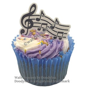 May include: A cupcake with purple and white frosting, decorated with a black and white musical note design. The cupcake sits in a blue paper case and is sprinkled with colourful sprinkles. The image includes the text "Wafertoppers by Doodylou".
