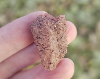 May include: A small, rough, pink and white crystal with a natural, irregular shape.