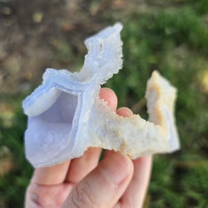 Close-up view of the raw African Blue Lace Agate cluster from an alternate angle, highlighting its complex, open-ended geometric shape, natural etching, and how the light catches the delicate blue and white bands.