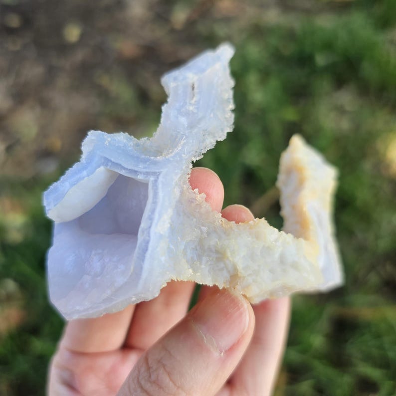 Close-up view of the raw African Blue Lace Agate cluster from an alternate angle, highlighting its complex, open-ended geometric shape, natural etching, and how the light catches the delicate blue and white bands.