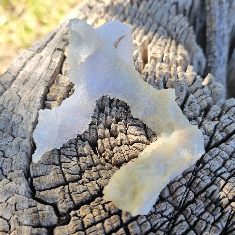 Close-up view of the raw African Blue Lace Agate cluster from an alternate angle, highlighting its complex, open-ended geometric shape, natural etching, and how the light catches the delicate blue and white bands.