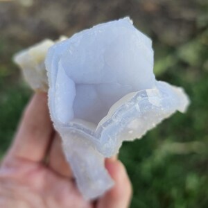 Close-up view of the raw African Blue Lace Agate cluster from an alternate angle, highlighting its complex, open-ended geometric shape, natural etching, and how the light catches the delicate blue and white bands.