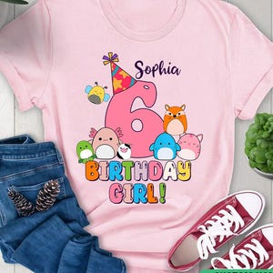 Puede incluir: Camiseta rosa con un gráfico colorido de un número 6 rodeado de animales de dibujos animados. El texto "Sophia 6 Birthday Girl!" está en la camiseta.