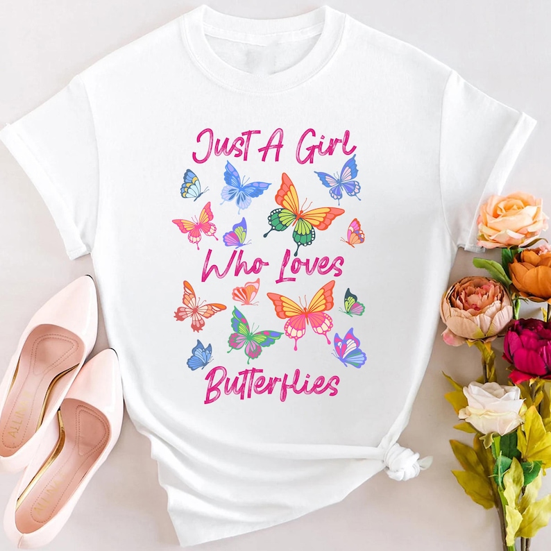 May include: White t-shirt with a pink graphic that says "Just a Girl Who Loves Butterflies". The graphic features colorful butterflies.