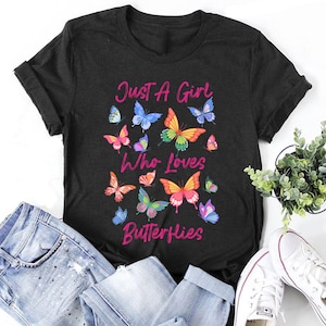 May include: Black t-shirt with the text "Just a Girl Who Loves Butterflies" in pink lettering. The shirt is decorated with colorful butterfly illustrations.
