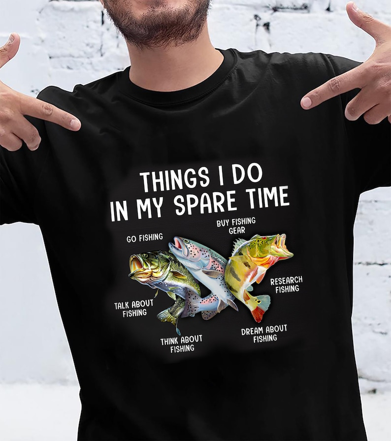 May include: A black t-shirt with white text that reads "Things I do in my spare time."  The text is surrounded by illustrations of fish, including a bass, a trout, and a perch.  The text below the fish reads "Go fishing", "Buy fishing gear", "Talk about fishing", "Research fishing", "Think about fishing", and "Dream about fishing."